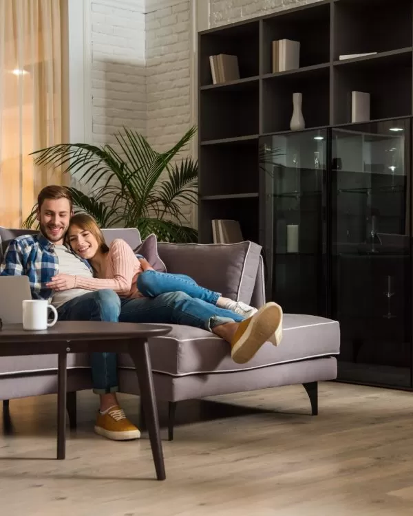 couple sitting on couch in living room with newly installed hardwood flooring